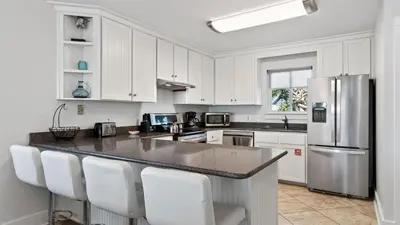 a kitchen with white cabinets and a granite counter top at Sandy Pelican by AvantStay Exclusive Beach Access Private Pool Firepit Balcony Sunset Views in Seacrest
