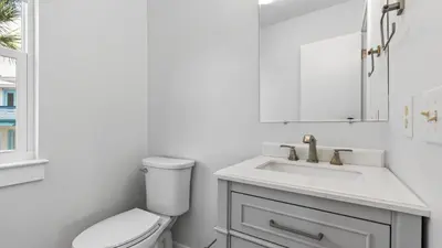 a white bathroom with a toilet and a sink at Sandy Pelican by AvantStay Exclusive Beach Access Private Pool Firepit Balcony Sunset Views in Seacrest