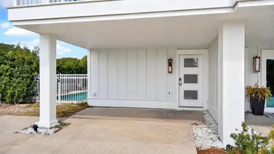 a white house with a white door and a porch at Sandy Pelican by AvantStay Exclusive Beach Access Private Pool Firepit Balcony Sunset Views in Seacrest