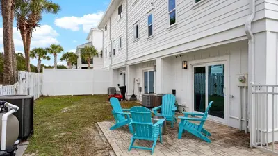 a patio with blue chairs and a table at Sandy Pelican by AvantStay Exclusive Beach Access Private Pool Firepit Balcony Sunset Views in Seacrest