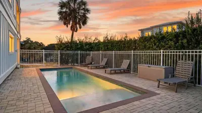 a swimming pool with two chairs and a fence at Sandy Pelican by AvantStay Exclusive Beach Access Private Pool Firepit Balcony Sunset Views in Seacrest