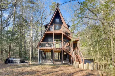 a large wooden house in the woods at Near Hiking! Angler Oasis with Hot Tub in Florida