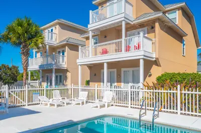 a villa with a swimming pool and a house at Beach Getaway for 15 A Few Steps from the Sand in Panama City Beach