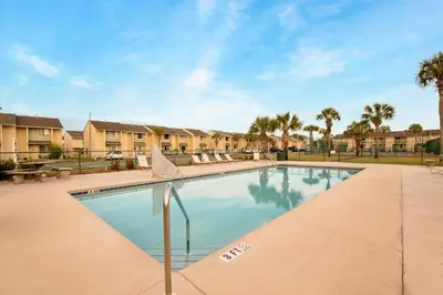 a swimming pool with palm trees and condos at Gulf Highlands #195 in Panama City Beach