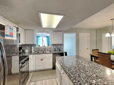 a kitchen with white cabinets and granite counter tops at Gulf Highlands #195 in Panama City Beach