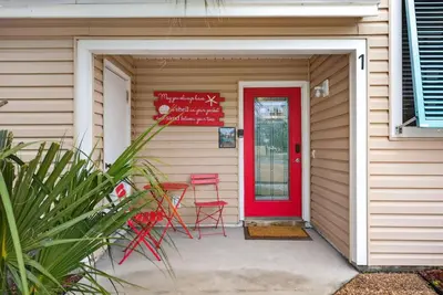 a red door on a house with two red chairs at Emerald Escape 1 - 3 Blocks to Beach in Panama City Beach