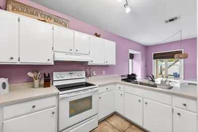 a kitchen with white cabinets and purple walls at Emerald Escape - 3 Blocks to Beach in Panama City Beach