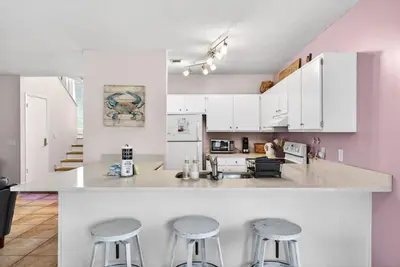 a kitchen with white cabinets and bar stools at Emerald Escape - 3 Blocks to Beach in Panama City Beach