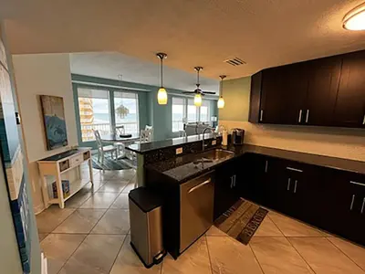 a kitchen with black cabinets and a living room at Seychelles 701 by Emerald Coast Retreats in Panama City Beach