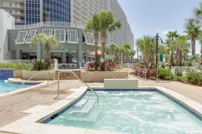 a swimming pool with palm trees and a building at Laketown Wharf Beach Resort in Panama City Beach