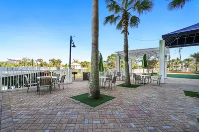 a patio with tables and chairs and palm trees at Laketown Wharf Beach Resort in Panama City Beach