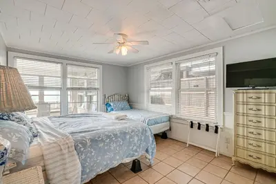 a bedroom with a bed and a tv and windows at Two by Sea Beachfront Private Home with Courtyard! in Panama City Beach