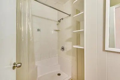 a white bathroom with a shower and a toilet at Two by Sea Beachfront Private Home with Courtyard! in Panama City Beach