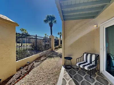 a porch of a house with a bench and a palm tree at Gulf Highlands #134F in Panama City Beach