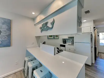 a kitchen with a white counter and stools at Gulf Highlands #134F in Panama City Beach