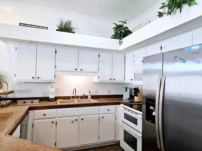 a kitchen with white cabinets and a stainless steel refrigerator at You, Me & the Sea! in Panama City Beach