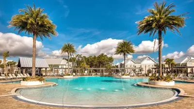 a swimming pool with palm trees in a resort at Prominence 14B in Rosemary Beach