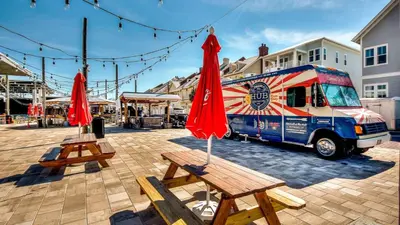 two tables with red umbrellas in front of a food truck at Prominence 14B in Rosemary Beach