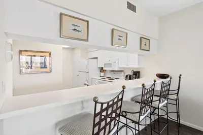 a kitchen with a bar with chairs and a table at High Pointe 431 Gulf Views in Rosemary Beach