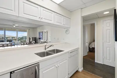 a kitchen with white cabinets and a sink and a table at High Pointe 431 Gulf Views in Rosemary Beach