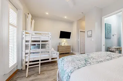 a white bedroom with a bed and a tv at Spacious Home with Private Pool dog-friendly 2 Blocks to Beach in Santa Rosa Beach