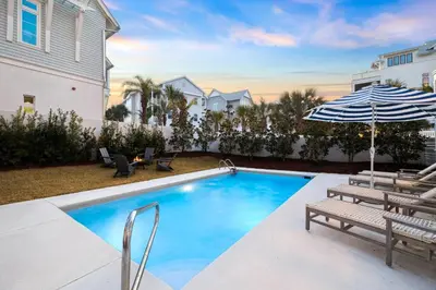 a swimming pool with an umbrella and chairs and a house at Beach,Please in Rosemary Beach