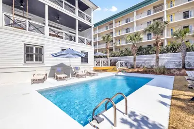 a pool with chairs and an umbrella next to a building at Beach,Please in Rosemary Beach