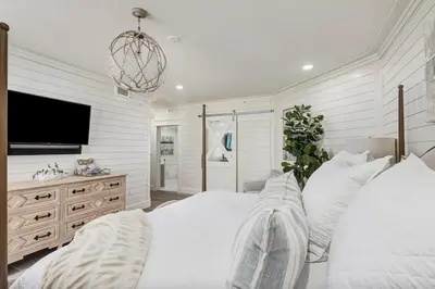 a white bedroom with a large bed and a flat screen tv at Stunning beachfront condo with shared pool & beach access in Santa Rosa Beach