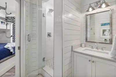 a white bathroom with a shower and a sink at Stunning beachfront condo with shared pool & beach access in Santa Rosa Beach