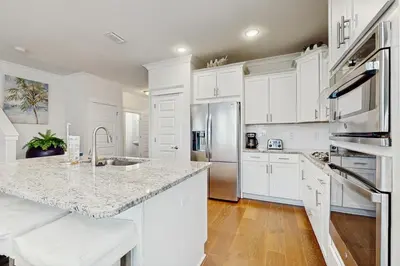 a kitchen with white cabinets and a marble counter top at Home with pool & dock access - blocks to beach Powell Lake & state park in Inlet Beach