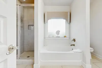a white bathroom with a tub and a shower at Home with pool & dock access - blocks to beach Powell Lake & state park in Inlet Beach