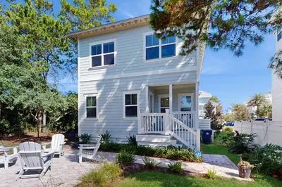 a white house with white chairs on a patio at Home with pool & dock access - blocks to beach Powell Lake & state park in Inlet Beach