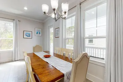 a dining room with a wooden table and windows at Lovely Two-Story Home with Porches Access to Pool & Dock in Inlet Beach