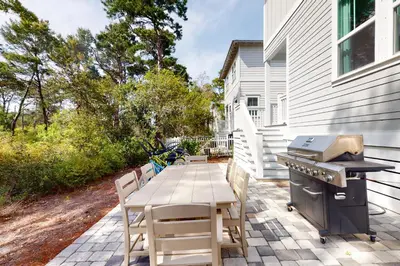 a patio with a grill and a table and chairs at Lovely Two-Story Home with Porches Access to Pool & Dock in Inlet Beach