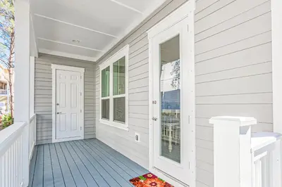 a porch with white siding and a white door at Lovely Two-Story Home with Porches Access to Pool & Dock in Inlet Beach