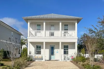a white house with a balcony on top of it at Brand-new house on Powell Lake near beach & 30A with pool W&D & gym in Inlet Beach