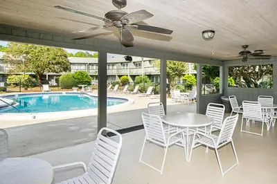 a patio with a table and chairs and a pool at Beautiful coastal studio condo with pool in Santa Rosa Beach