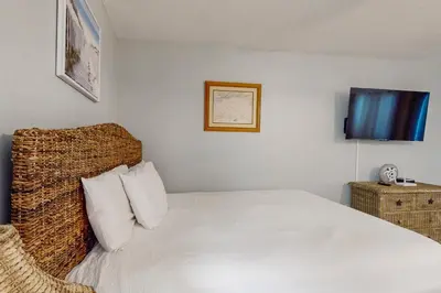 a bedroom with a white bed with a woven headboard at Beautiful coastal studio condo with pool in Santa Rosa Beach