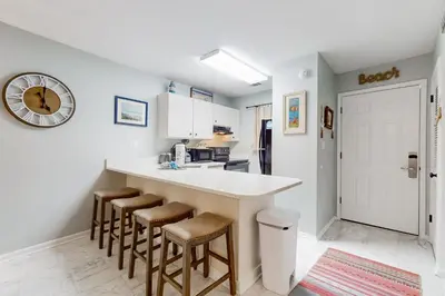 a kitchen with a counter with stools and a clock on the wall at Beautiful coastal studio condo with pool in Santa Rosa Beach