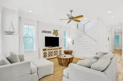 a white living room with two white couches and a tv at Relaxing getaway outdoor pool access gym bikes central AC & W&D in Inlet Beach
