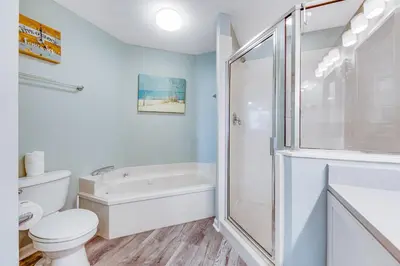 a white bathroom with a shower and a toilet at First-floor condo with sauna gym pool tennis & pickleball in Santa Rosa Beach