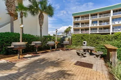 a patio with benches and picnic tables in front of a building at First-floor condo with sauna gym pool tennis & pickleball in Santa Rosa Beach
