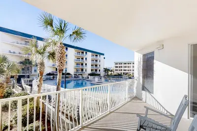 a balcony with a view of a swimming pool and palm trees at Condo with 2 stunning pools hot tub gym partial Gulf view & pickleball in Santa Rosa Beach