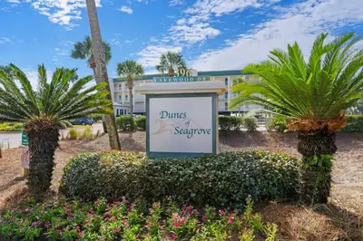 a sign in front of a hotel with palm trees at Condo with 2 stunning pools hot tub gym partial Gulf view & pickleball in Santa Rosa Beach