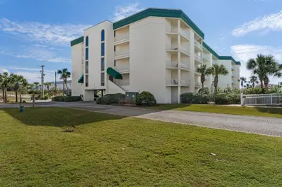 a large white building with palm trees in front of it at Condo with 2 stunning pools hot tub gym partial Gulf view & pickleball in Santa Rosa Beach