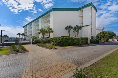 a white building with palm trees in front of it at Condo with 2 stunning pools hot tub gym partial Gulf view & pickleball in Santa Rosa Beach