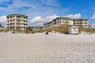 a building on the beach next to a sandy beach at Condo with 2 stunning pools hot tub gym partial Gulf view & pickleball in Santa Rosa Beach