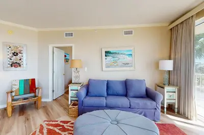 a living room with a blue couch and a window at Gulf-front 3-bedroom condo with bonus bunk room & pickleball in Santa Rosa Beach