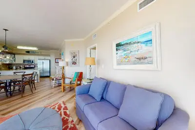 a living room with a blue couch and a table at Gulf-front 3-bedroom condo with bonus bunk room & pickleball in Santa Rosa Beach