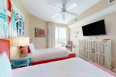 a bedroom with two beds and a flat screen tv at Gulf-front 3-bedroom condo with bonus bunk room & pickleball in Santa Rosa Beach